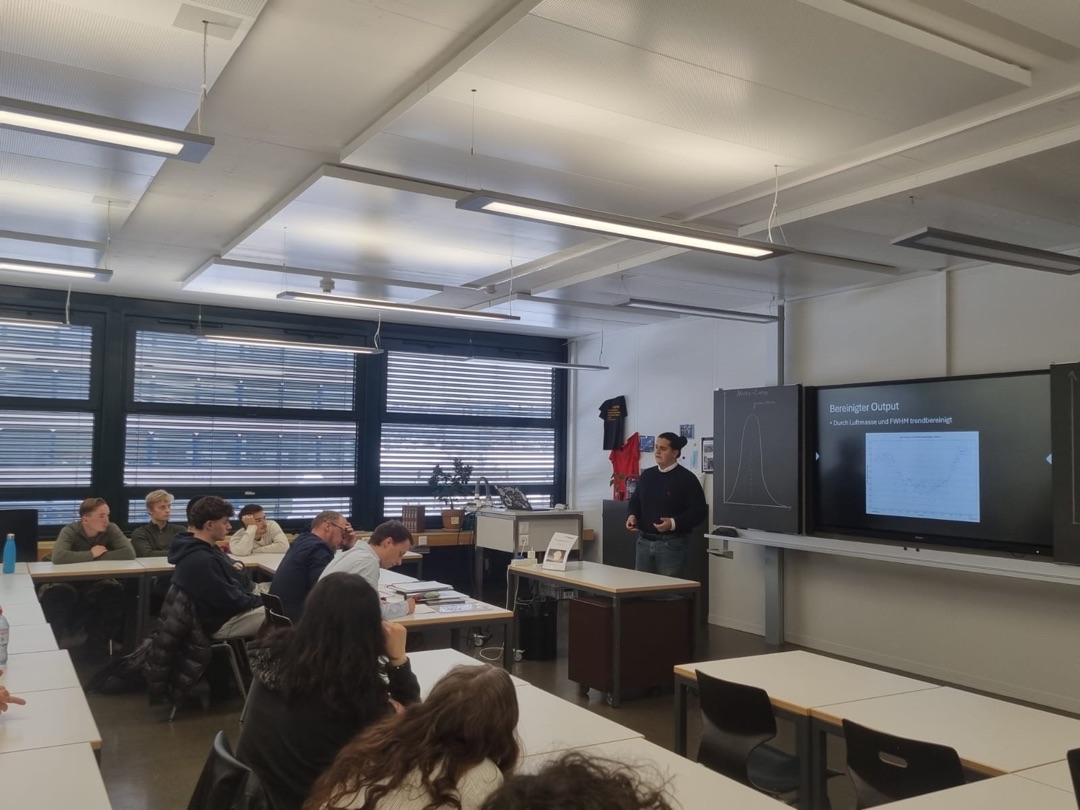 Nikola Knežević presenting the Matura thesis in a classroom at Kantonsschule Zofingen, with a light curve slide on the screen behind him.