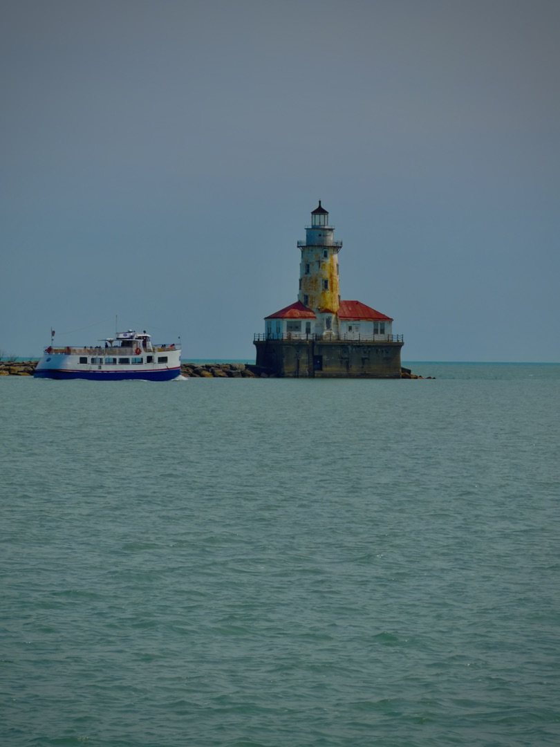 Chicago Harbor Lighthouse on Lake Michigan with a small tour boat passing