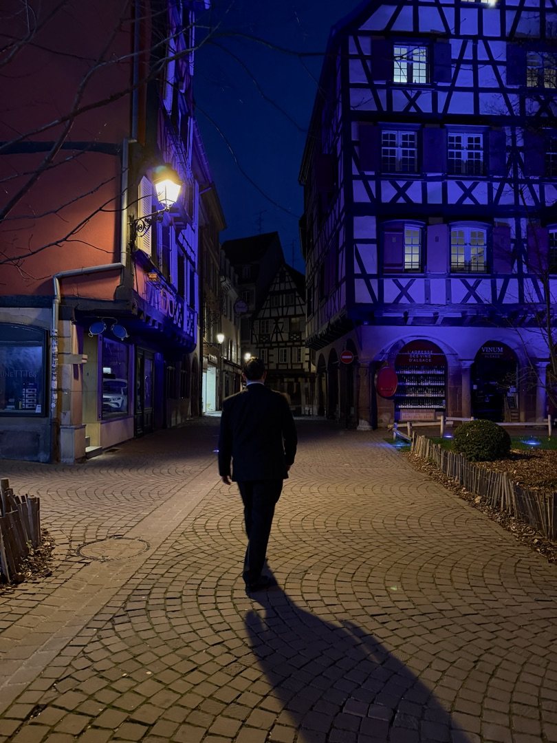 Half timbered Alsatian houses lit blue and amber at night in Colmar, France