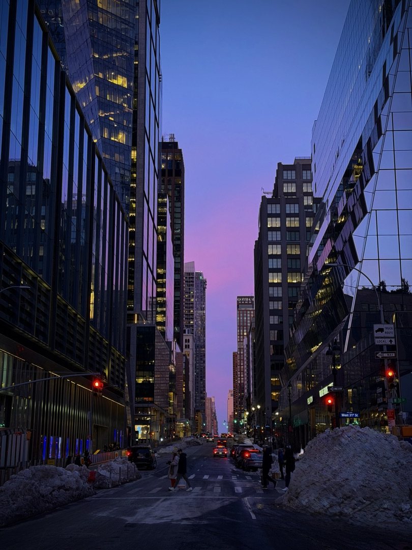 New York street at dusk with a pink and violet sky between skyscrapers on West 31st Street